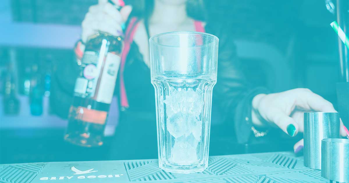 A BSU bartender pouring a drink over ice